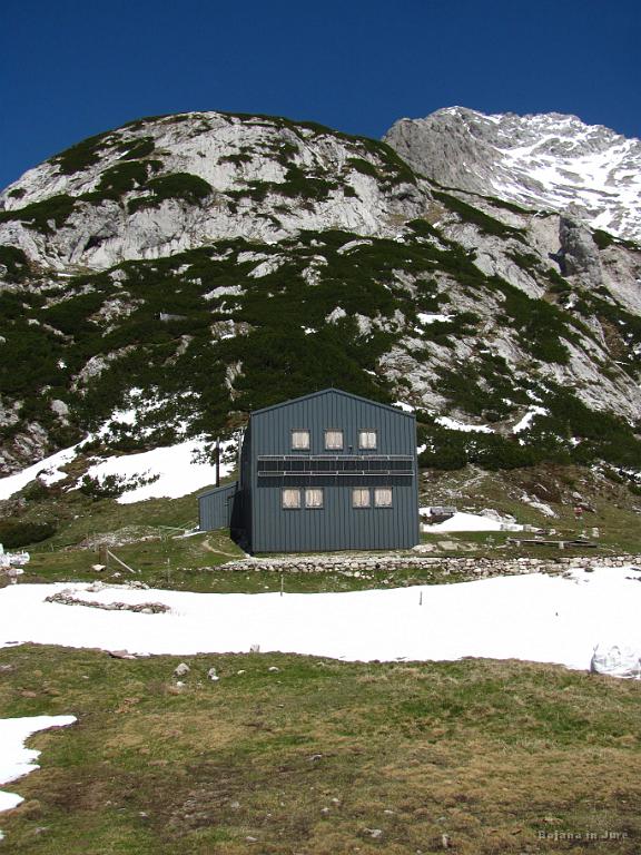 Slika_21.jpg - Kocbekov dom je še zaprt. Plato Korošica je sicer 100 m nižje od sedla Prag, in to leži na 1808 m. Do doma prispeva ob 11:30, torej po 3 urah in 50 minutah. Noge še povsem sveže, zato se le na kratko ustaviva in greva naprej.