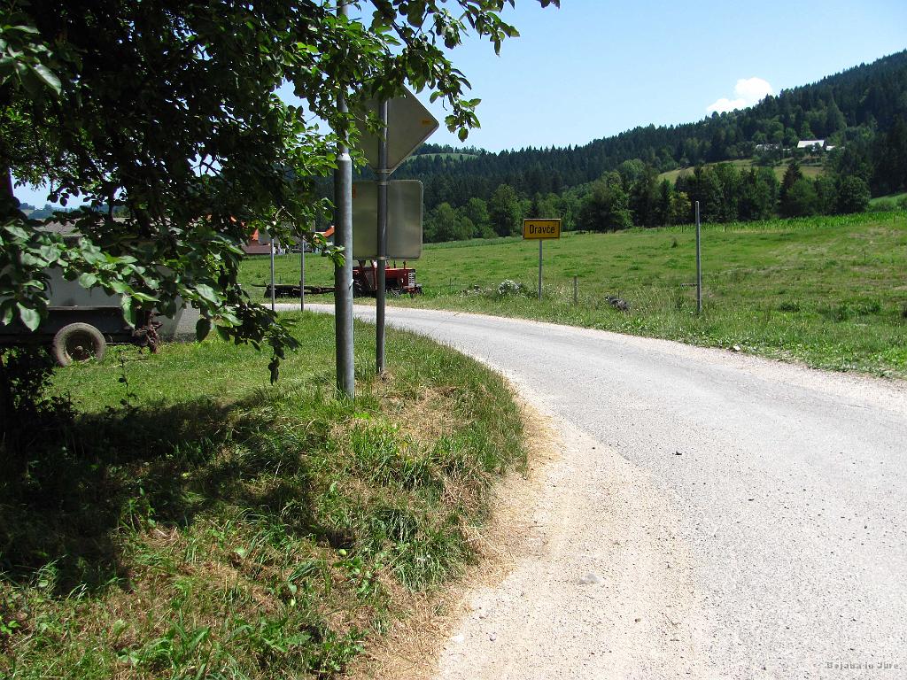 Slika_281.jpg - Vas Dravče. Tu se odcepi pot na levo proti Trbonjskem jezeru. Logika nama narekuje, da pot pač zavije daleč nazaj proti Trbonjam in da se nama ne splača, a dejstvo je, da je jezero tik za ovinkom pod Dravčami in se najverjetneje tako imenuje, ker se napaja iz izvira pri Trbonjah, ne pa ker bi bilo bliže le-teh. Malo nama je vseeno žal za zamujeno priložnost.